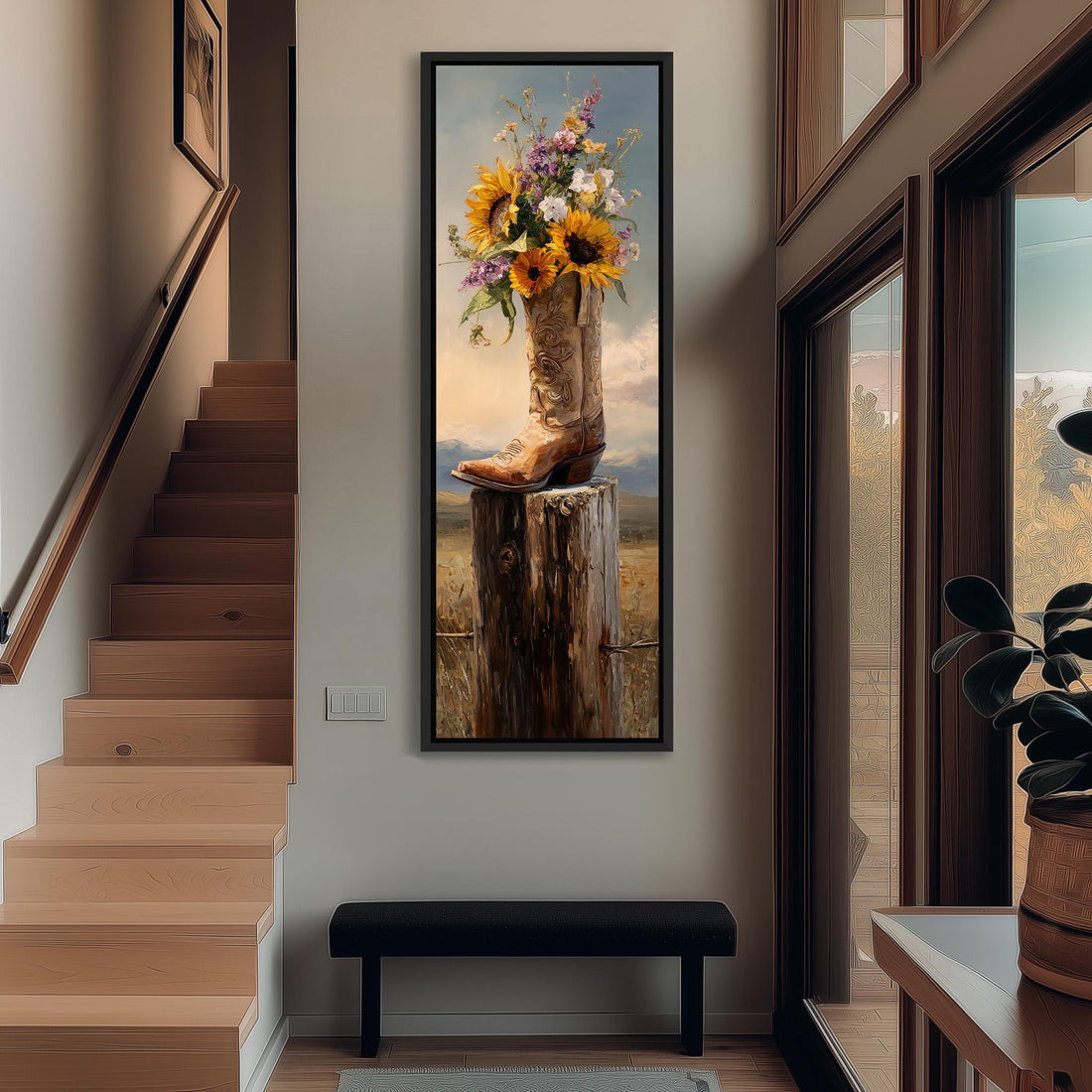 A framed painting of a cowboy boot filled with flowers is hanging on a wall in a room with a wooden floor and a window.