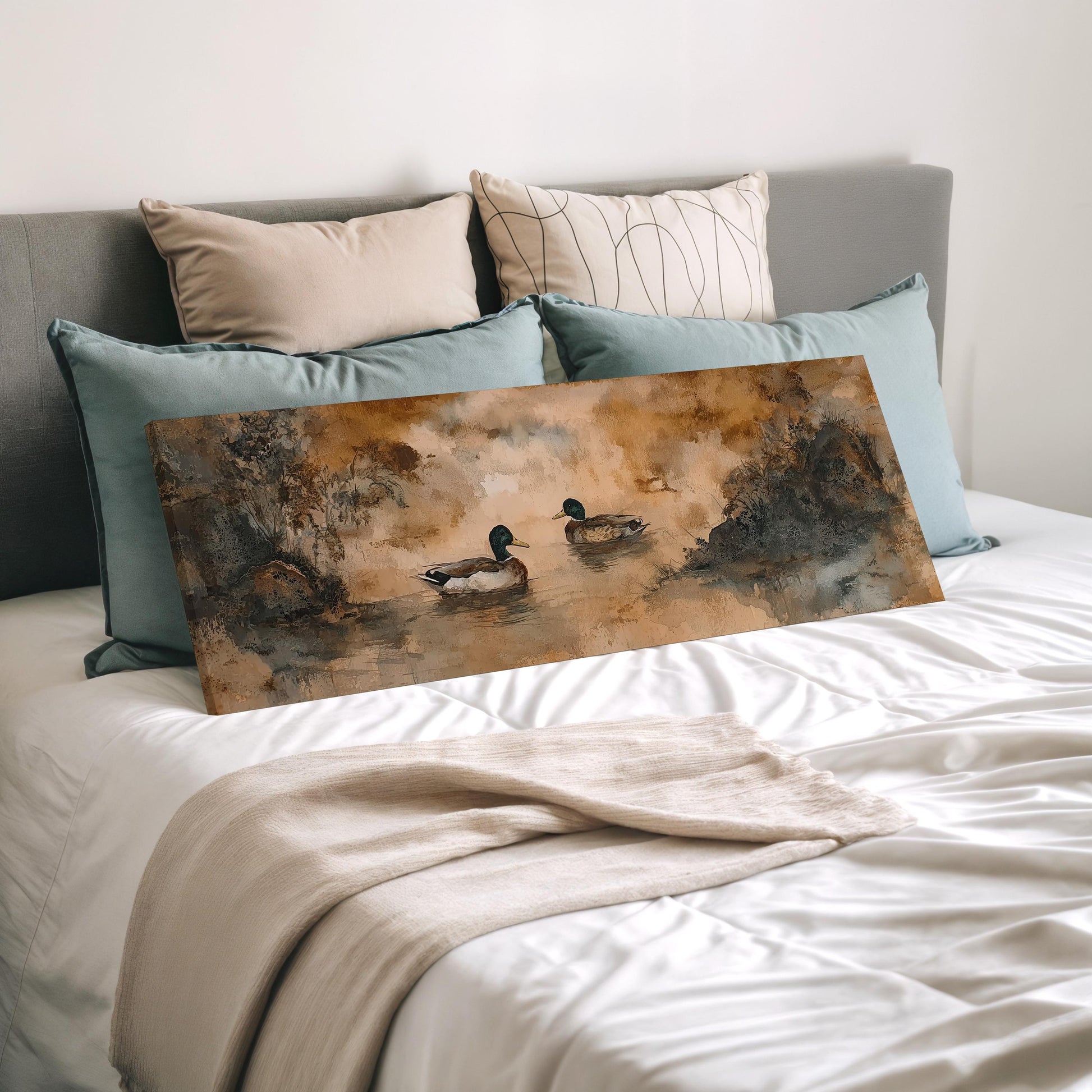 a bedroom with a bed and a painting of ducks on the bed. The painting is placed on the bed, which is covered with a white comforter and pillows.