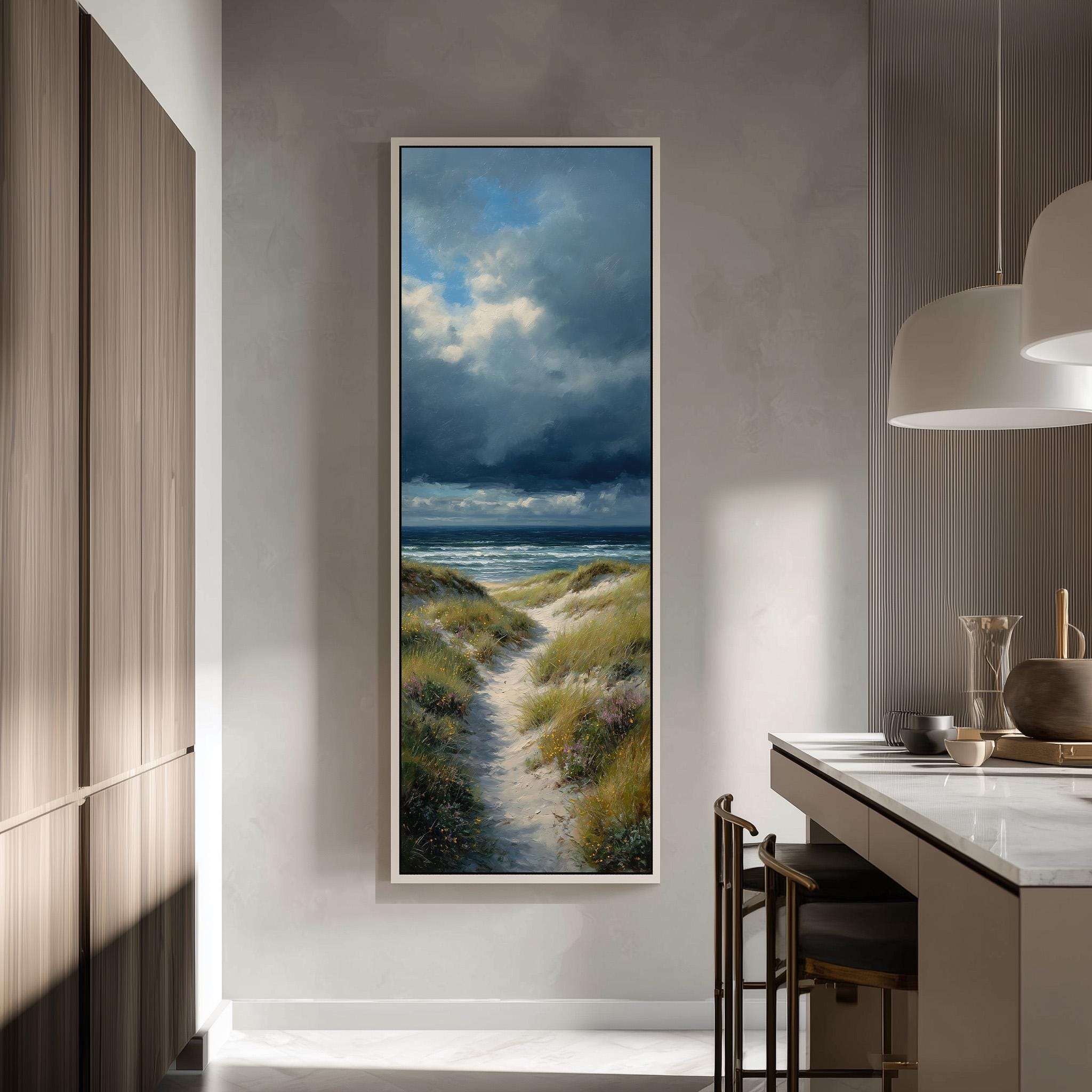 a large framed painting of a beach scene with a path leading to the ocean, hanging on a wall in a modern kitchen.