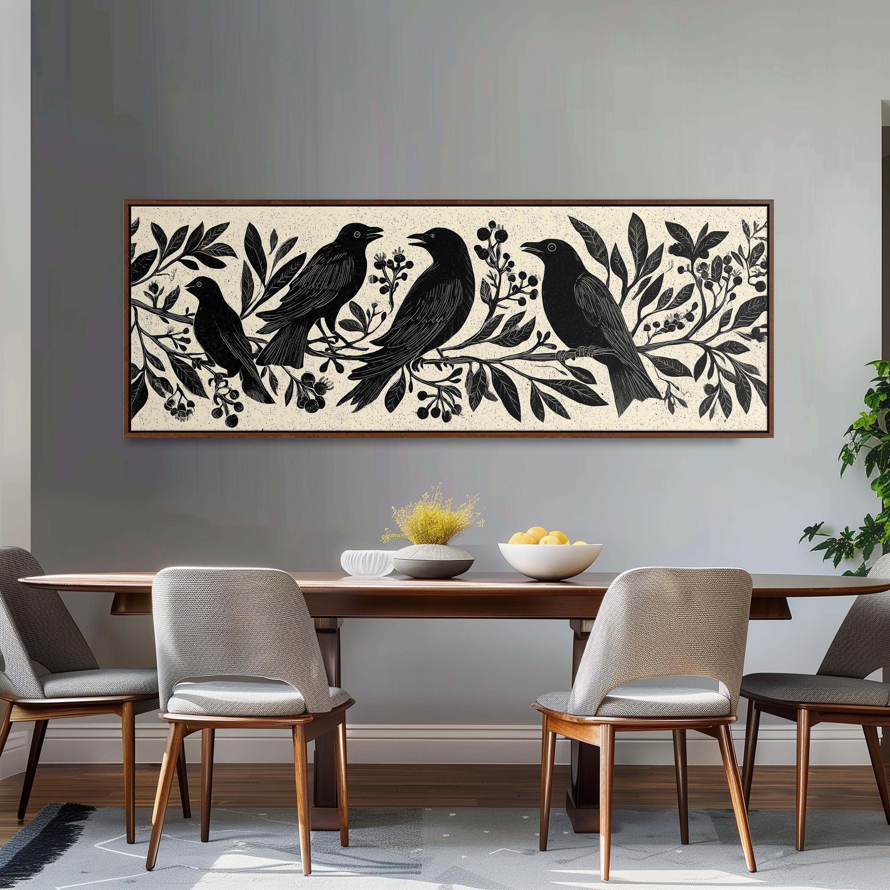 a dining room with a wooden table and four chairs. Above the table, there is a large framed artwork depicting a group of black birds perched on branches with leaves and berries. The artwork is framed in a brown frame and hangs on a gray wall.