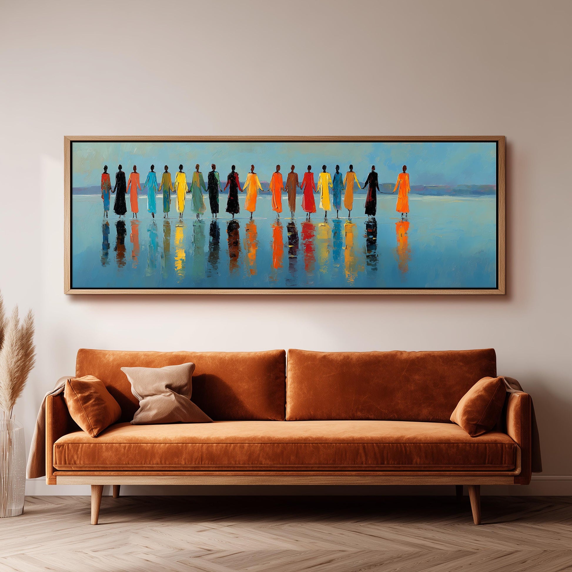 a large painting of a group of people standing in a line, with their reflections visible in the water below. The painting is hanging on a wall above a brown sofa, creating a cozy and inviting atmosphere in the room.