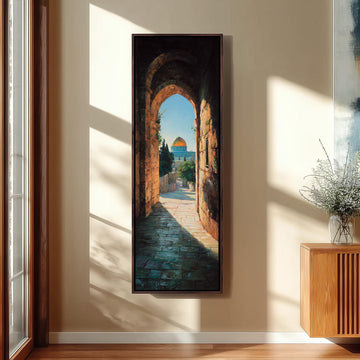 a large painting of a stone archway leading to a building with a dome, hanging on a wall in a room with a wooden floor and a window.