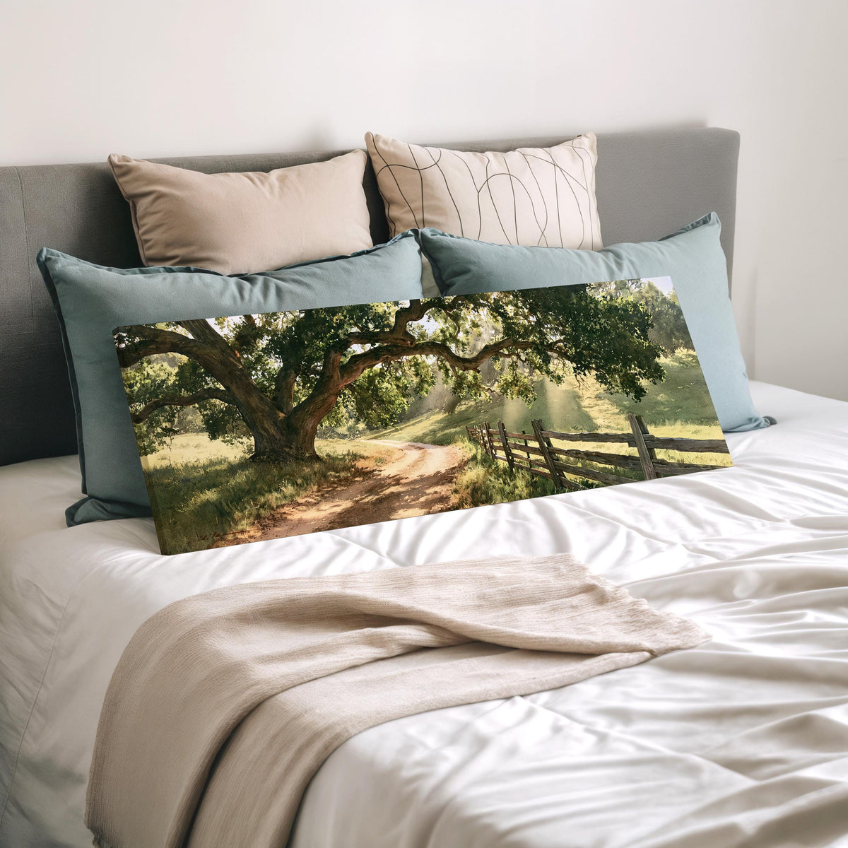Sunlit country lane with oak trees and a wooden fence wide panoramic canvas print laid on a bed to show its size