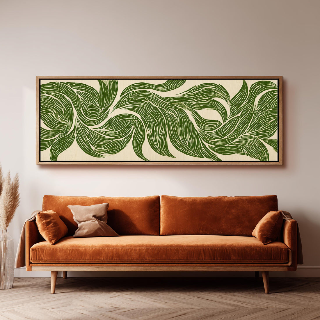 a large, framed artwork of green leaf patterns hanging on a wall above a brown sofa.