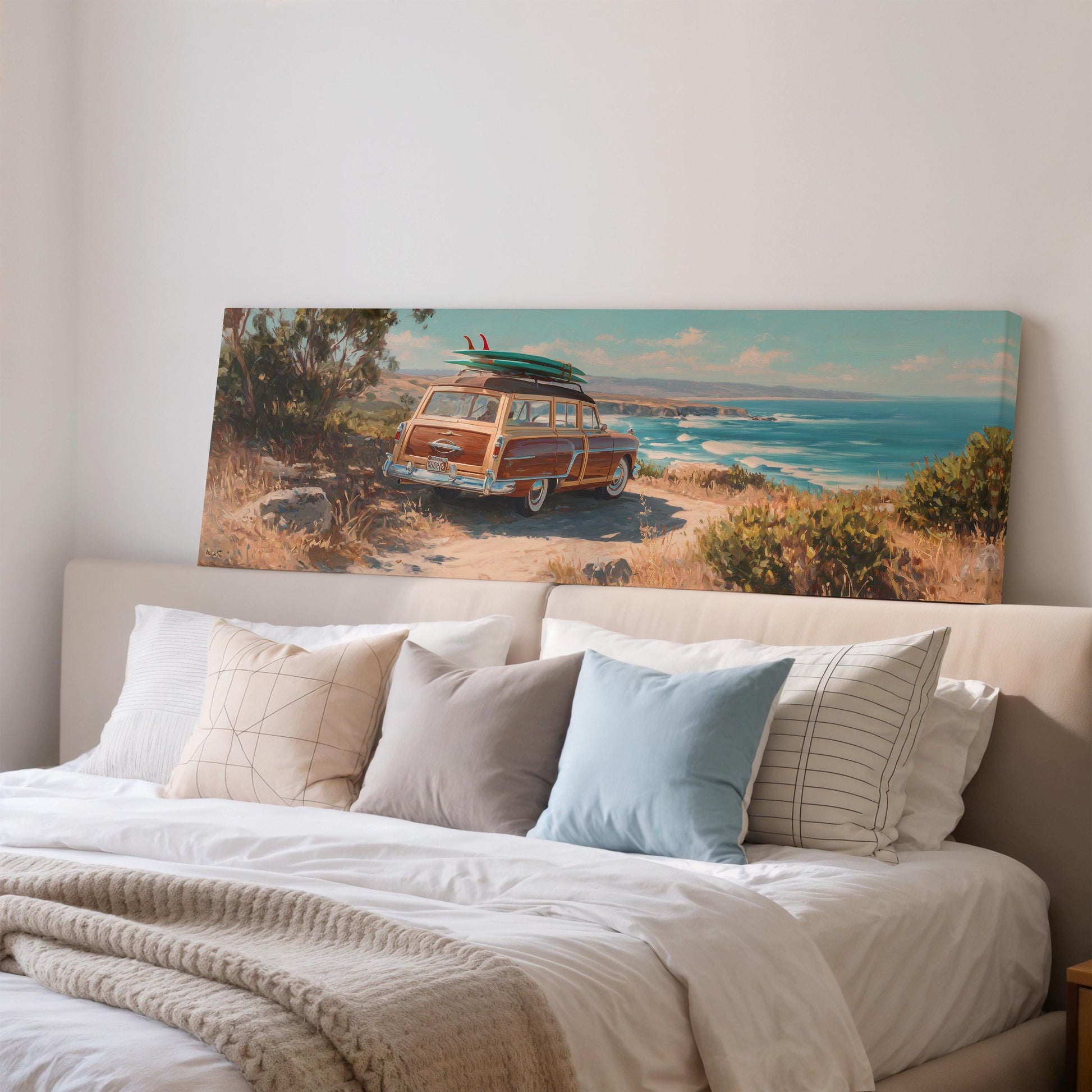 a large canvas print of a vintage car with a surfboard on top, displayed on a wall above a bed with white bedding and pillows.