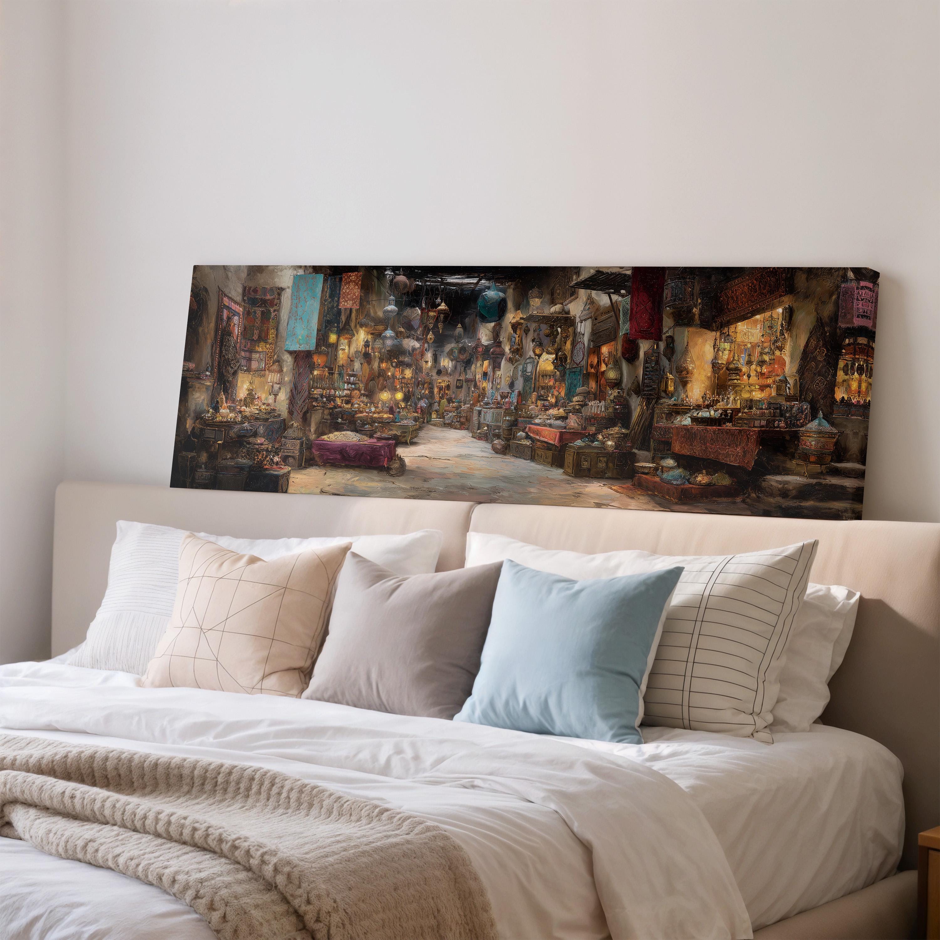 a large painting of a bustling market scene hanging on a wall above a bed with white pillows and a gray blanket.