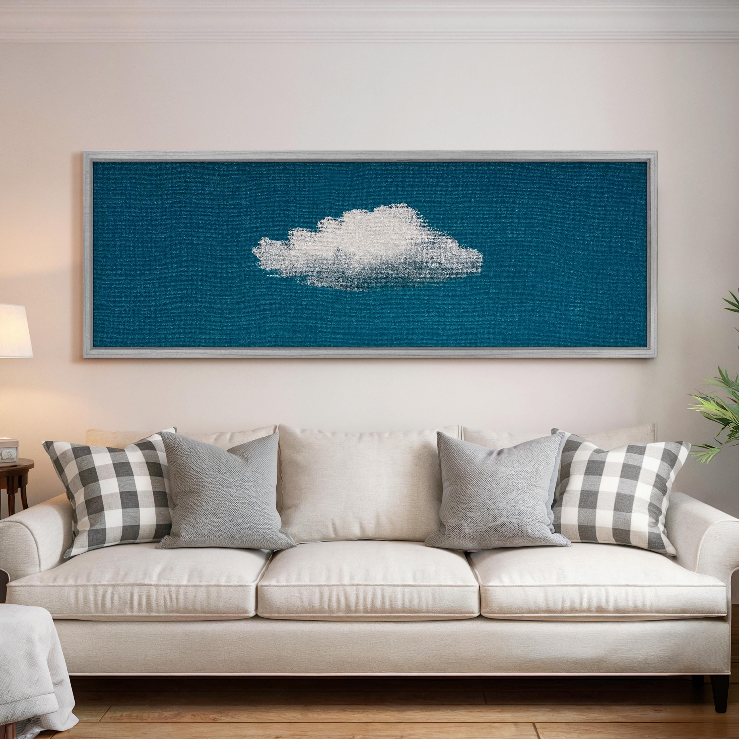 a white couch with gray and black plaid throw pillows, and a framed artwork of a cloud is displayed on the wall above it.