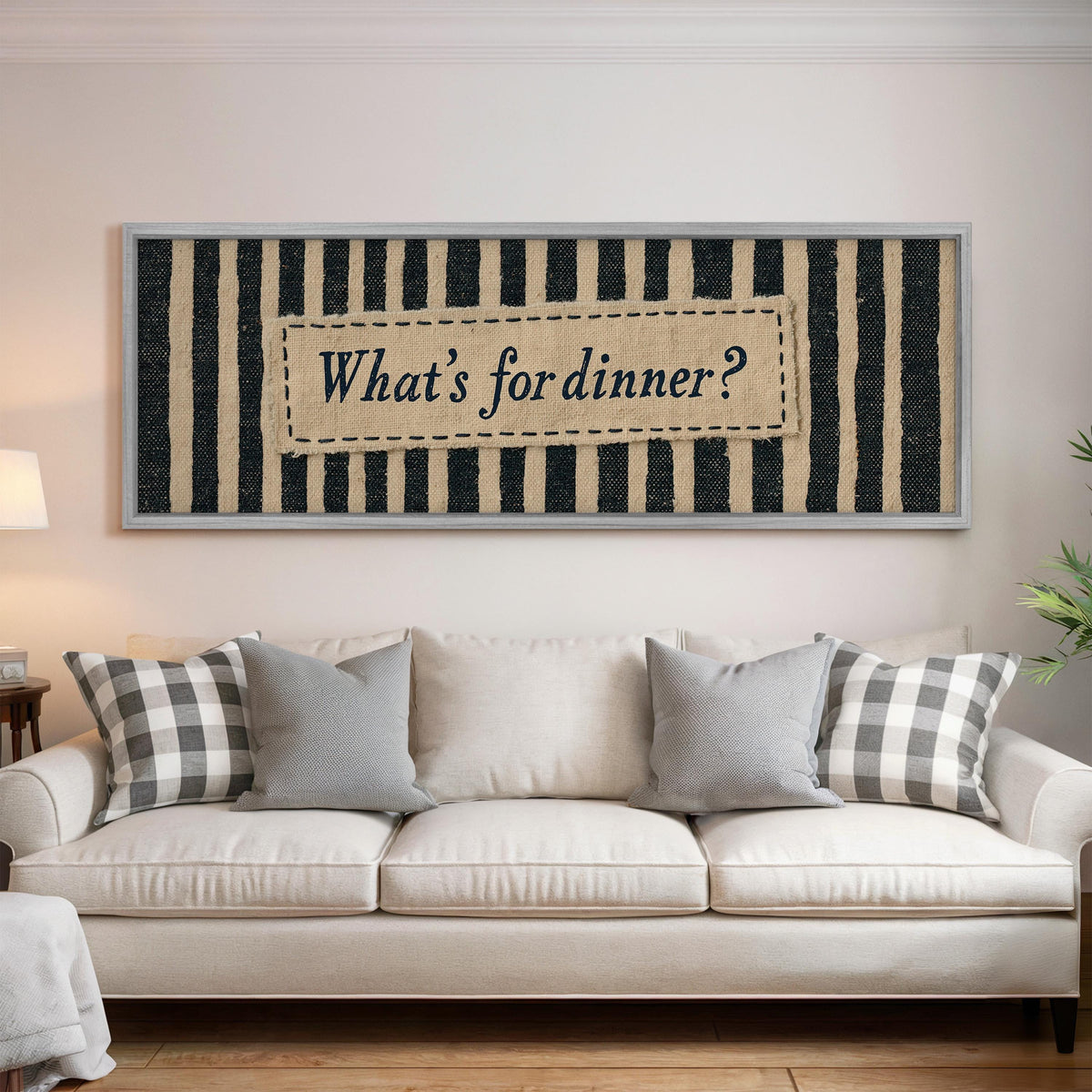 What's for dinner sign on black stripes panoramic canvas print above a white sofa in a bright living room