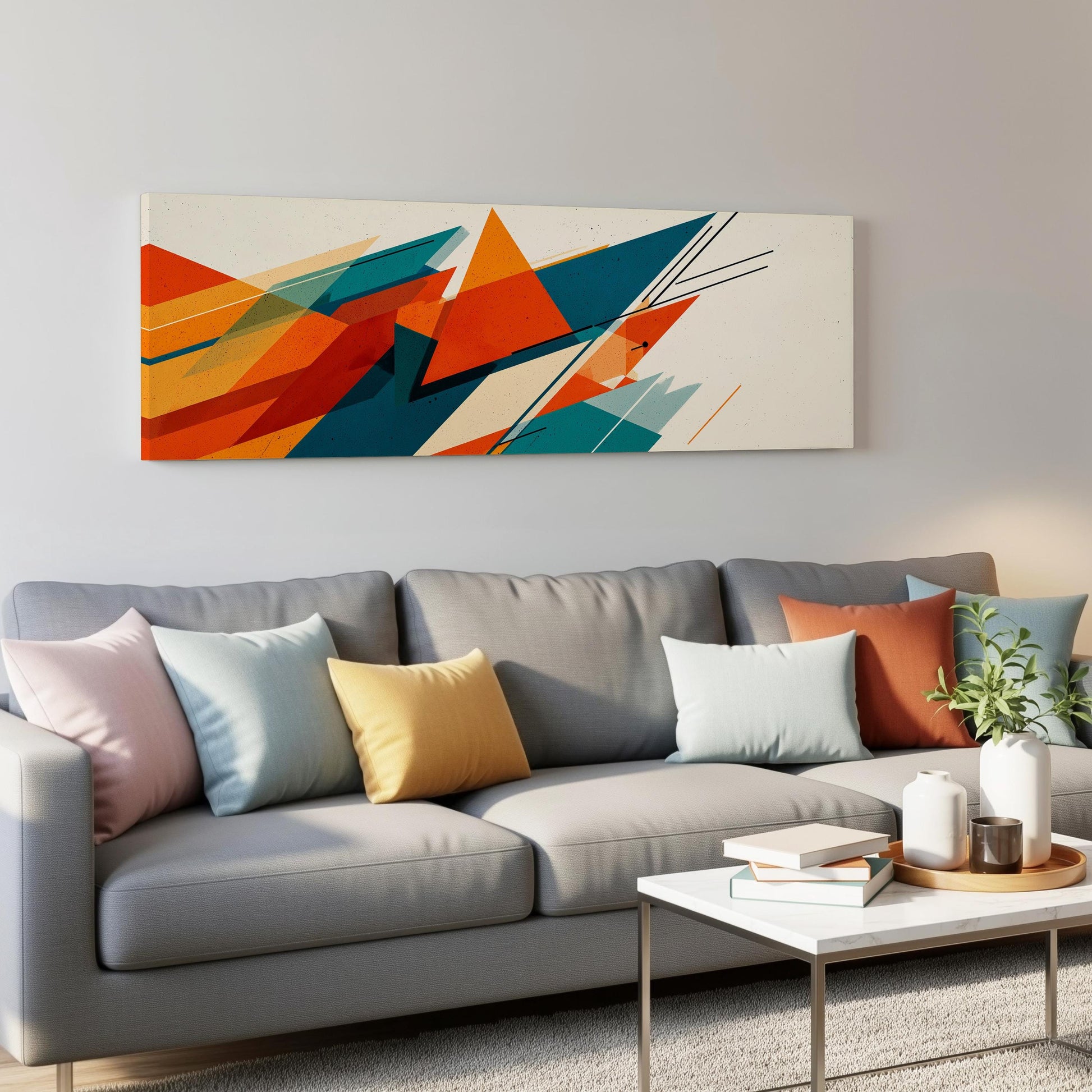 a modern living room with a gray sofa adorned with colorful throw pillows. Above the sofa, there is a large abstract painting with vibrant orange, blue, and green geometric shapes. The room also includes a coffee table with books and a plant, creating a cozy and inviting atmosphere.