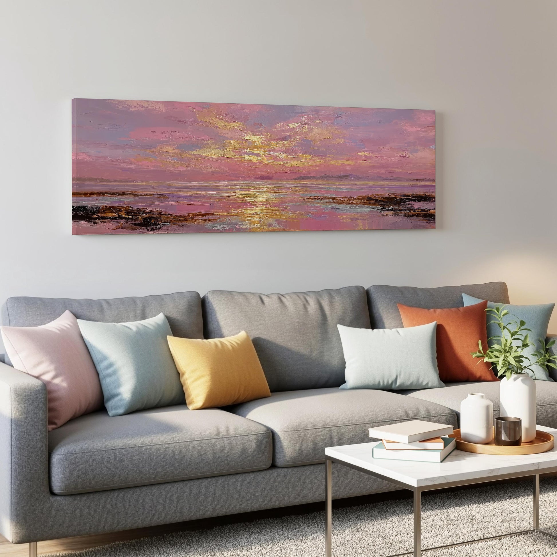 a large, colorful painting of a sunset over a body of water, hanging on a wall above a gray couch with colorful throw pillows.