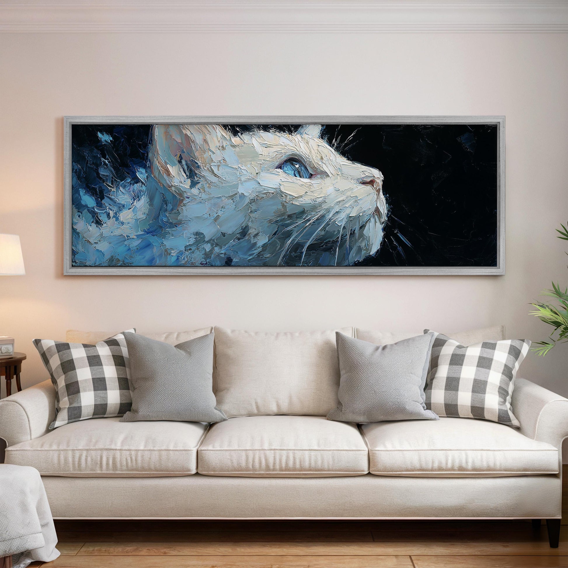 a large, framed painting of a cat's face hanging on a wall above a white couch with gray and white plaid throw pillows.