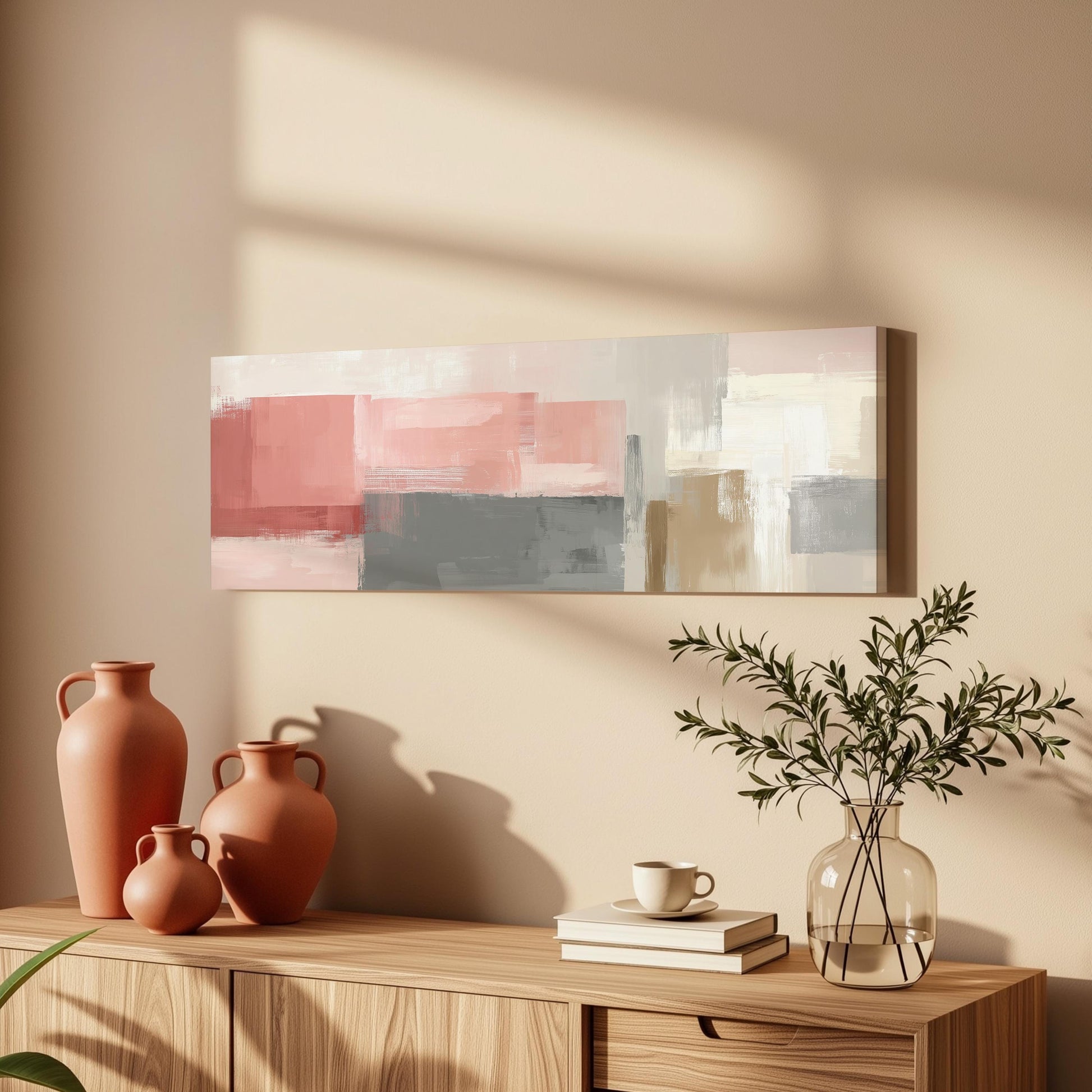 a wooden cabinet with a vase of greenery, a coffee cup, and a stack of books on top. Above the cabinet, there is a painting hanging on the wall.