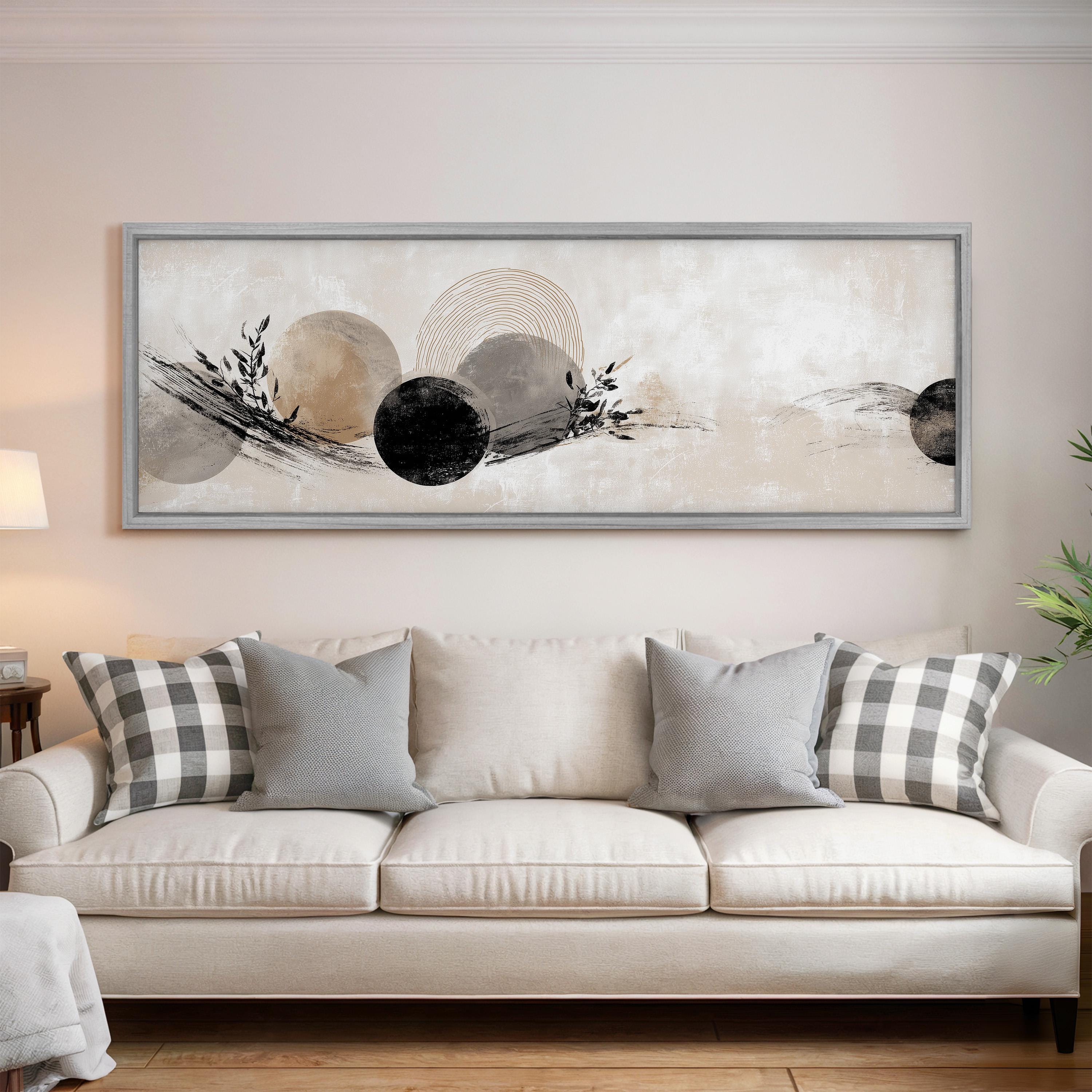a large, abstract painting hanging on a wall above a white couch with gray and white plaid throw pillows.