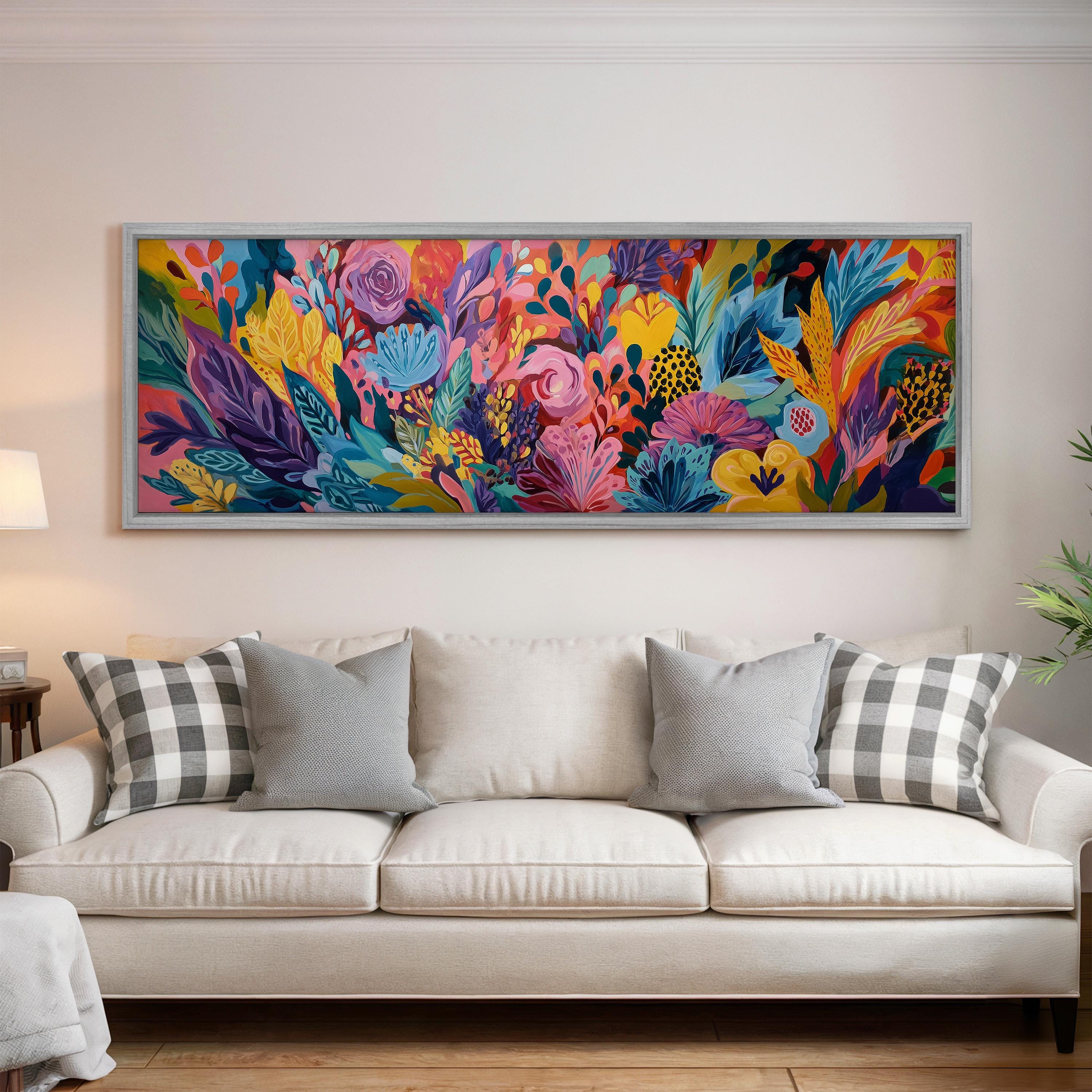 a large, colorful painting of a vibrant floral arrangement hanging on a wall above a white couch with gray and white plaid throw pillows.