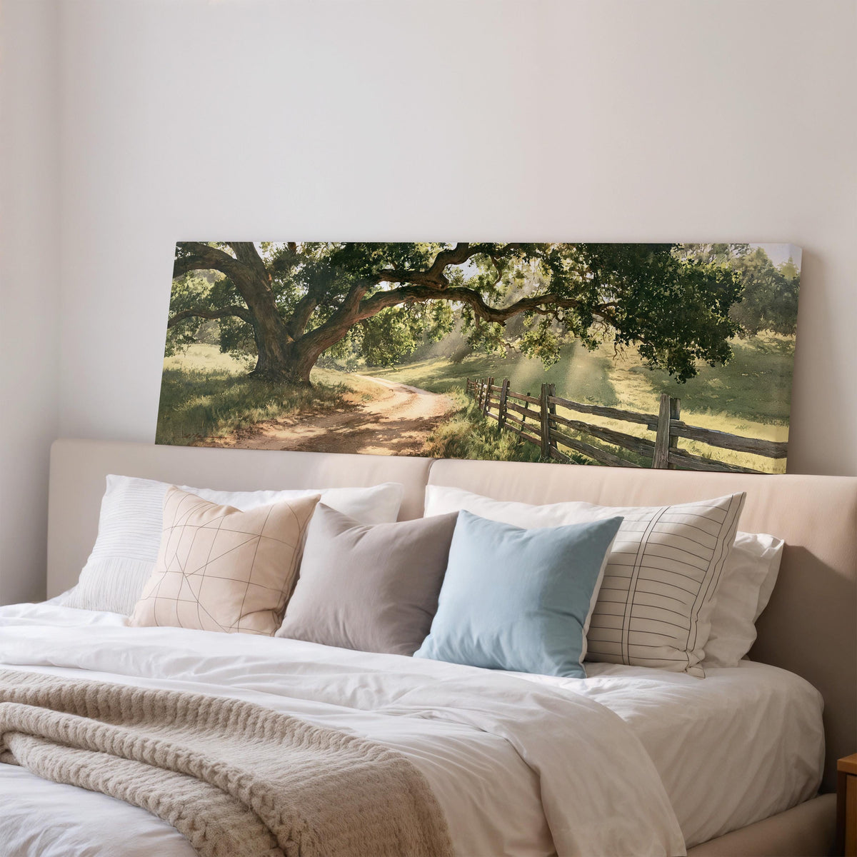 Sunlit country lane with oak trees and a wooden fence wide panoramic canvas print above a bed in a bedroom