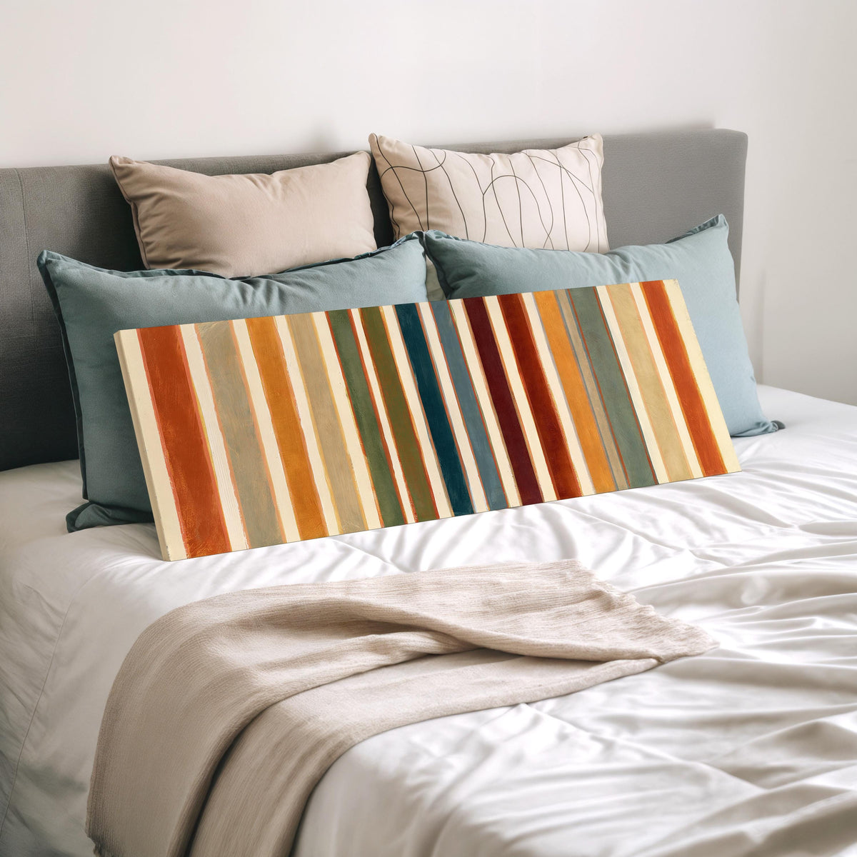 Rust, sage, maroon and teal stripes wide panoramic canvas print laid on a bed to show its size