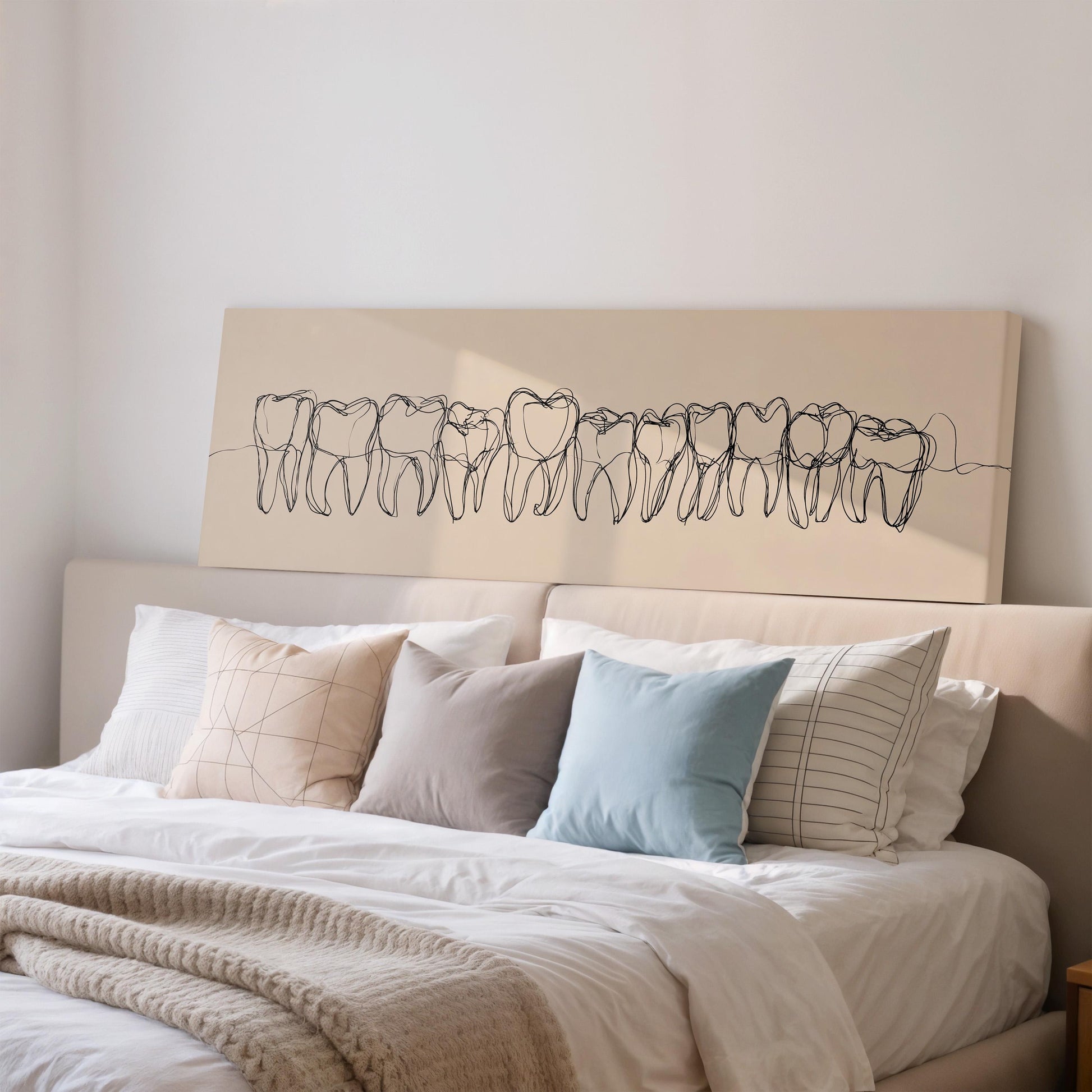 a bed with a white comforter and pillows, and above the bed is a large canvas print depicting a line of teeth.
