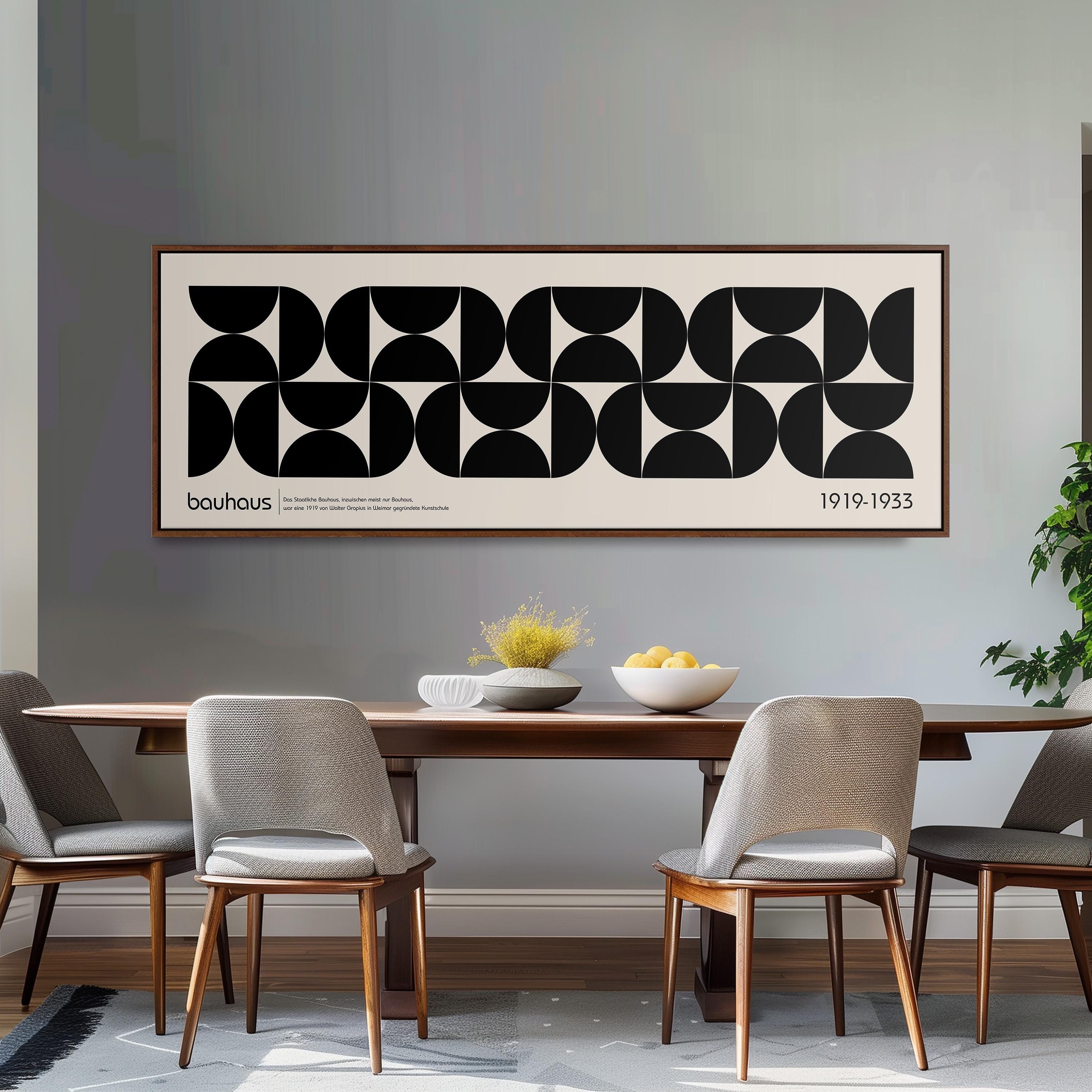 a dining room with a large black and white abstract art piece hanging on the wall above a wooden dining table with four chairs. The table is set with a bowl of fruit and a vase of flowers, creating a cozy and inviting atmosphere.
