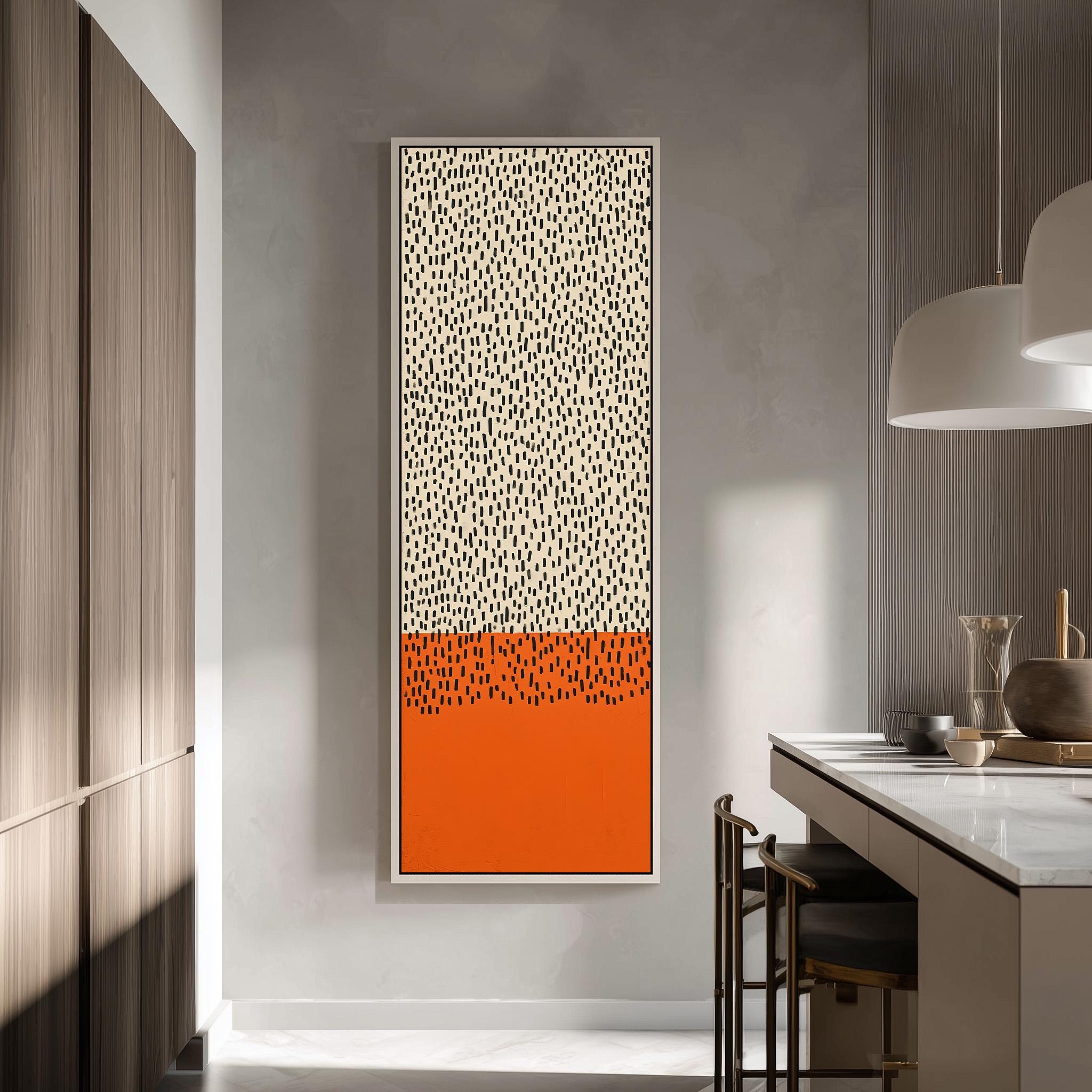 a modern kitchen with a large abstract painting hanging on the wall. The painting has a bold orange and white color scheme with a pattern of small dots or dots across the frame. The kitchen is equipped with a white countertop and a wooden cabinet, creating a clean and minimalist aesthetic.