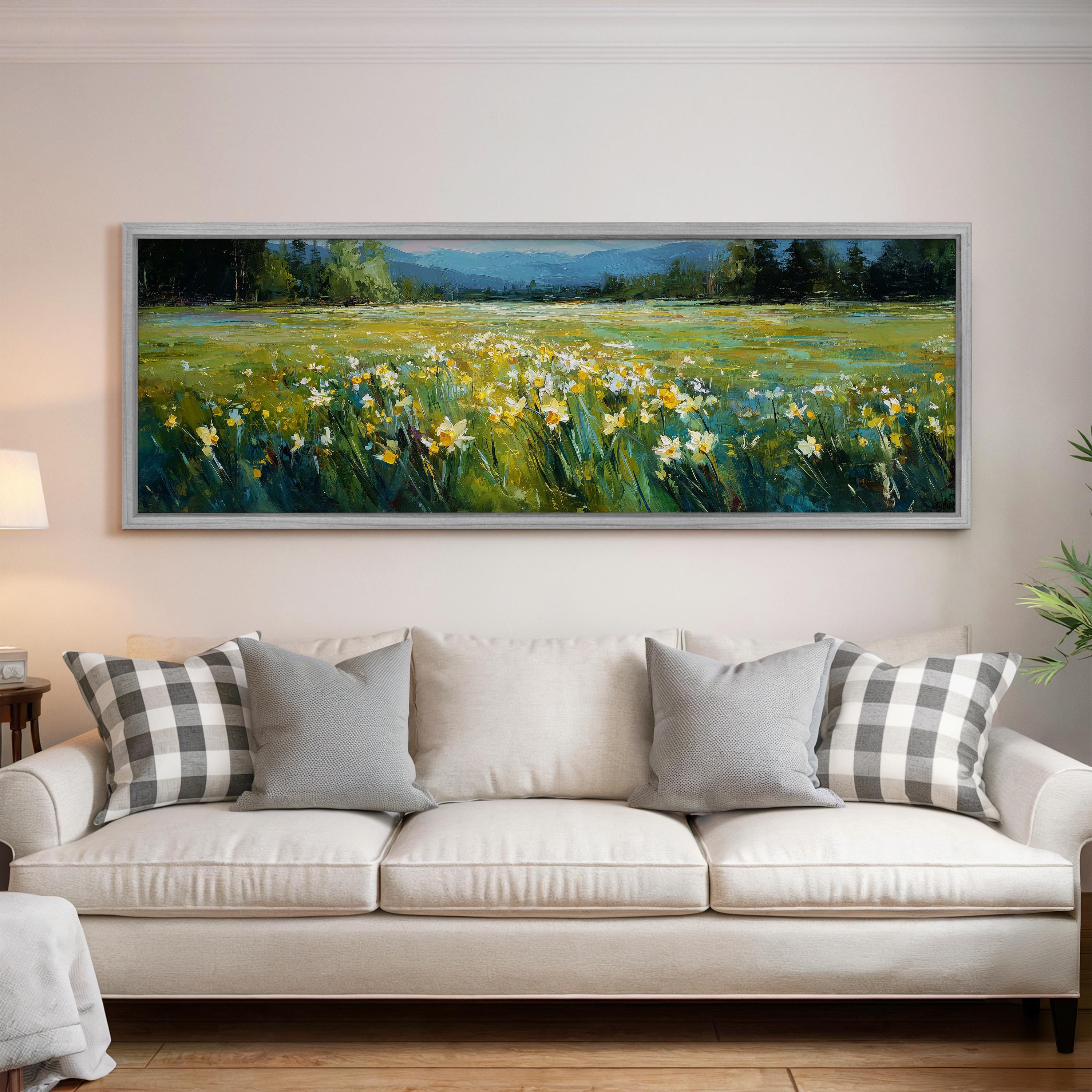 a large painting of a field with yellow flowers hanging on a wall above a white couch with gray and white pillows.