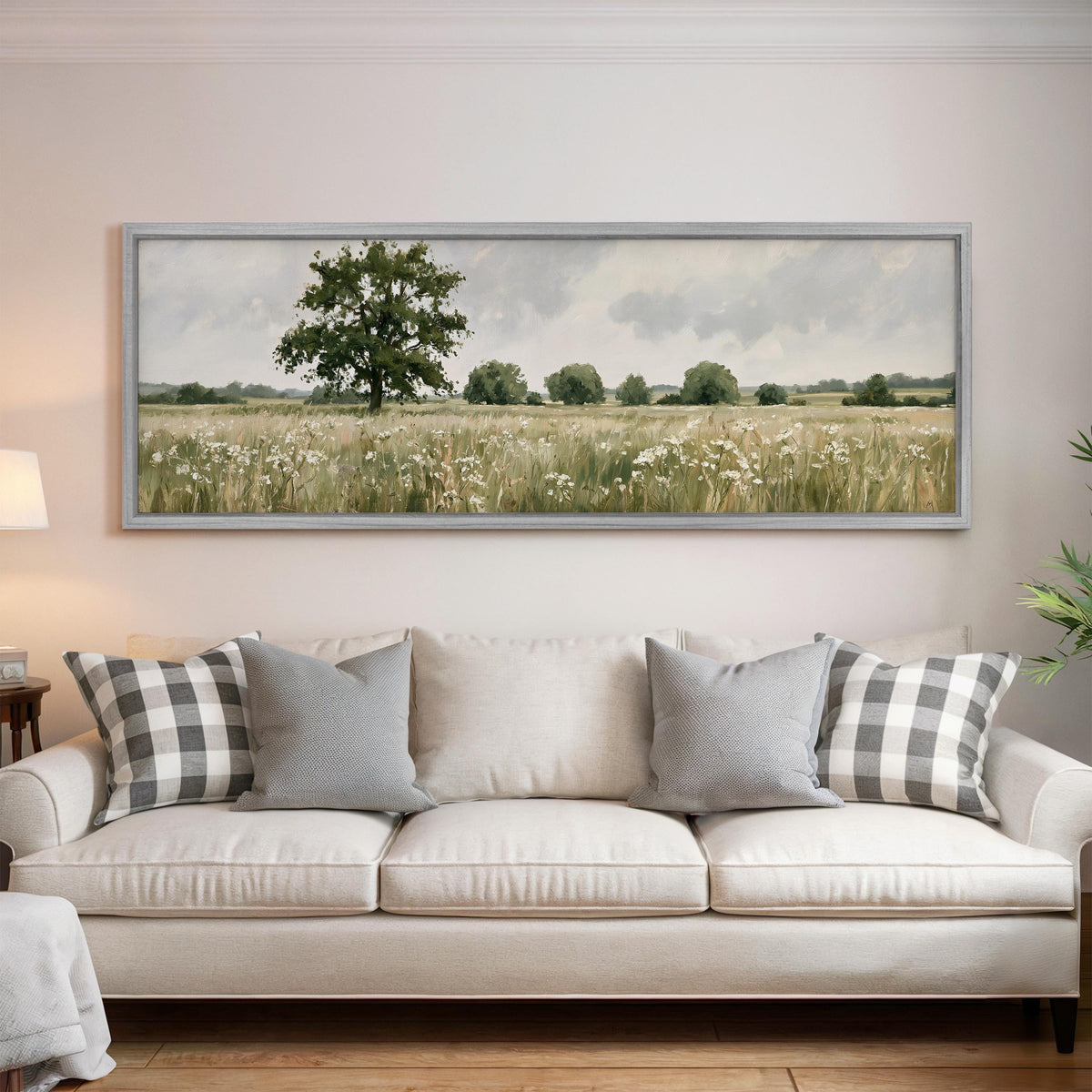 Lone oak tree in a daisy meadow panoramic canvas print above a white sofa in a bright living room