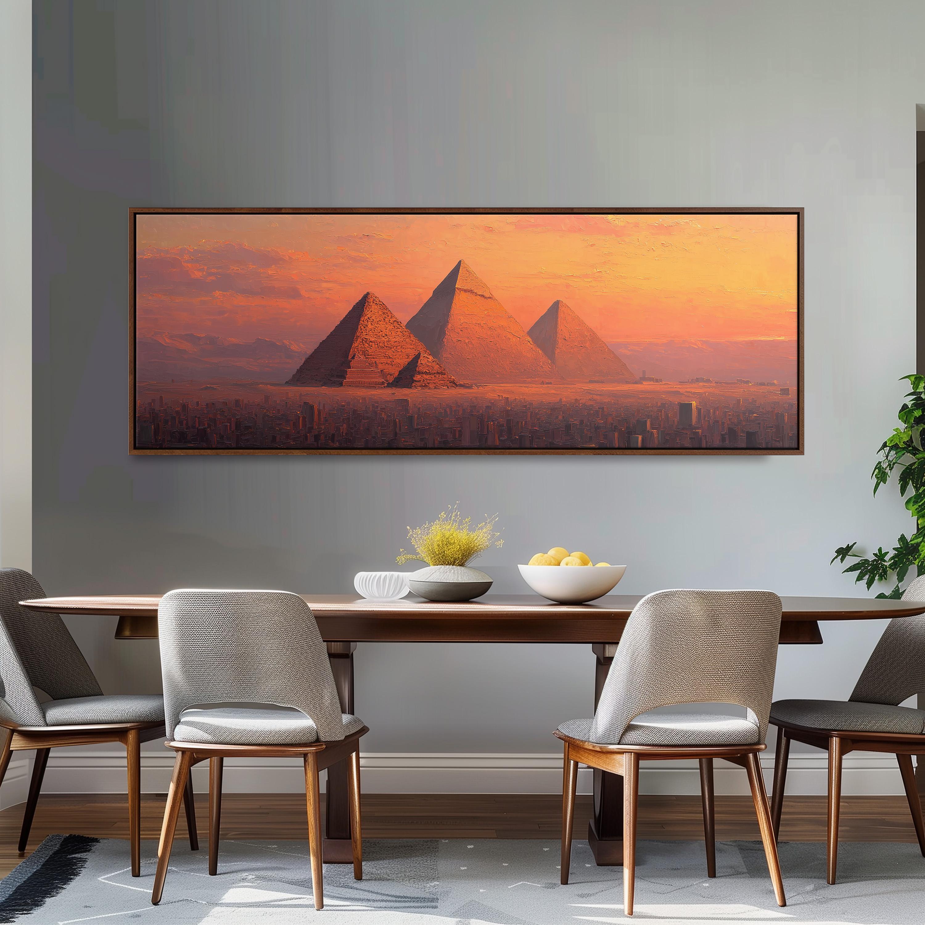 a large painting of the pyramids of Giza in Egypt, with a warm sunset in the background. The painting is hung on a wall above a wooden dining table with four chairs. The table is set with a bowl of fruit and a vase of flowers, creating a cozy and inviting atmosphere.