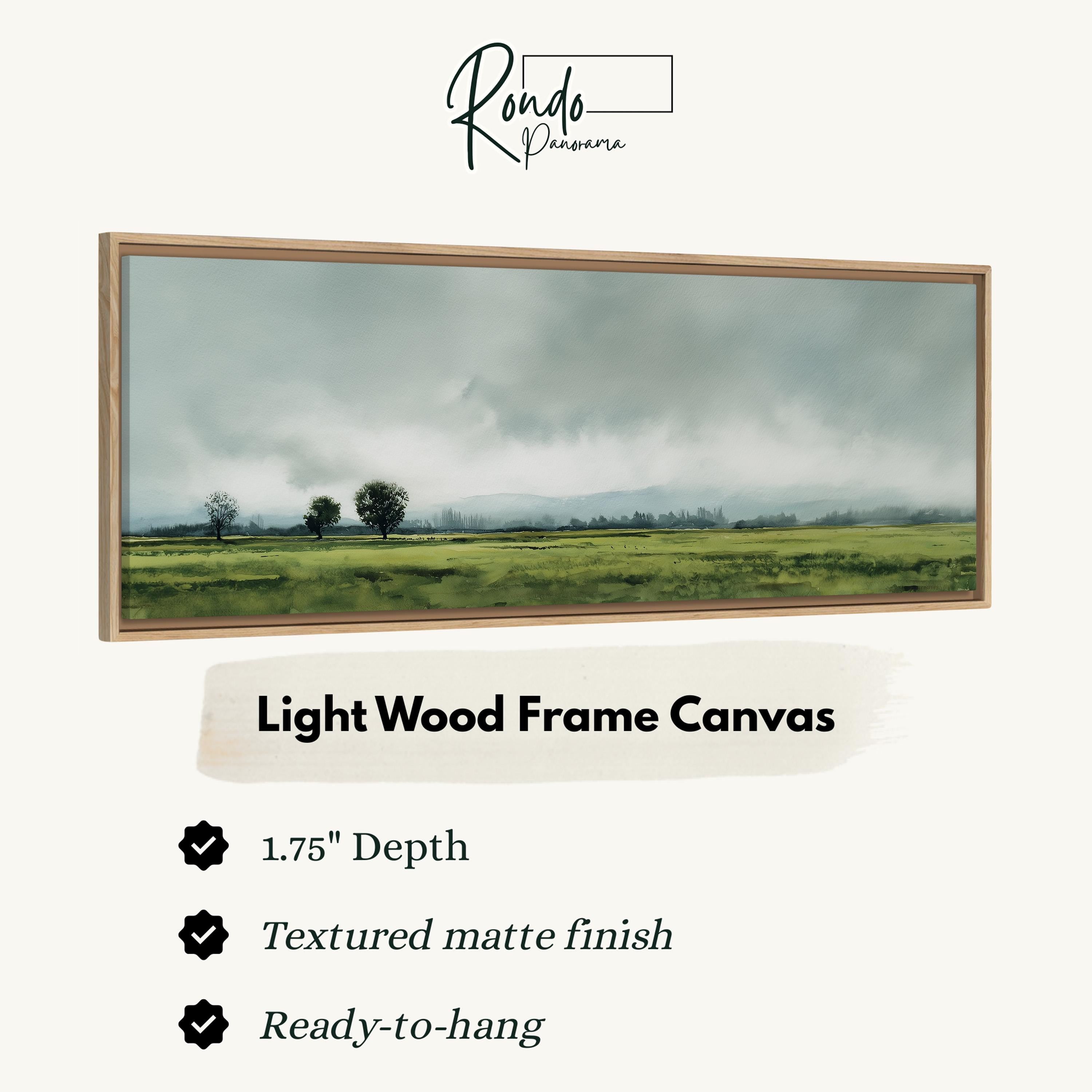 The image is a framed painting of a rural landscape with a field and trees, featuring a light wood frame.
