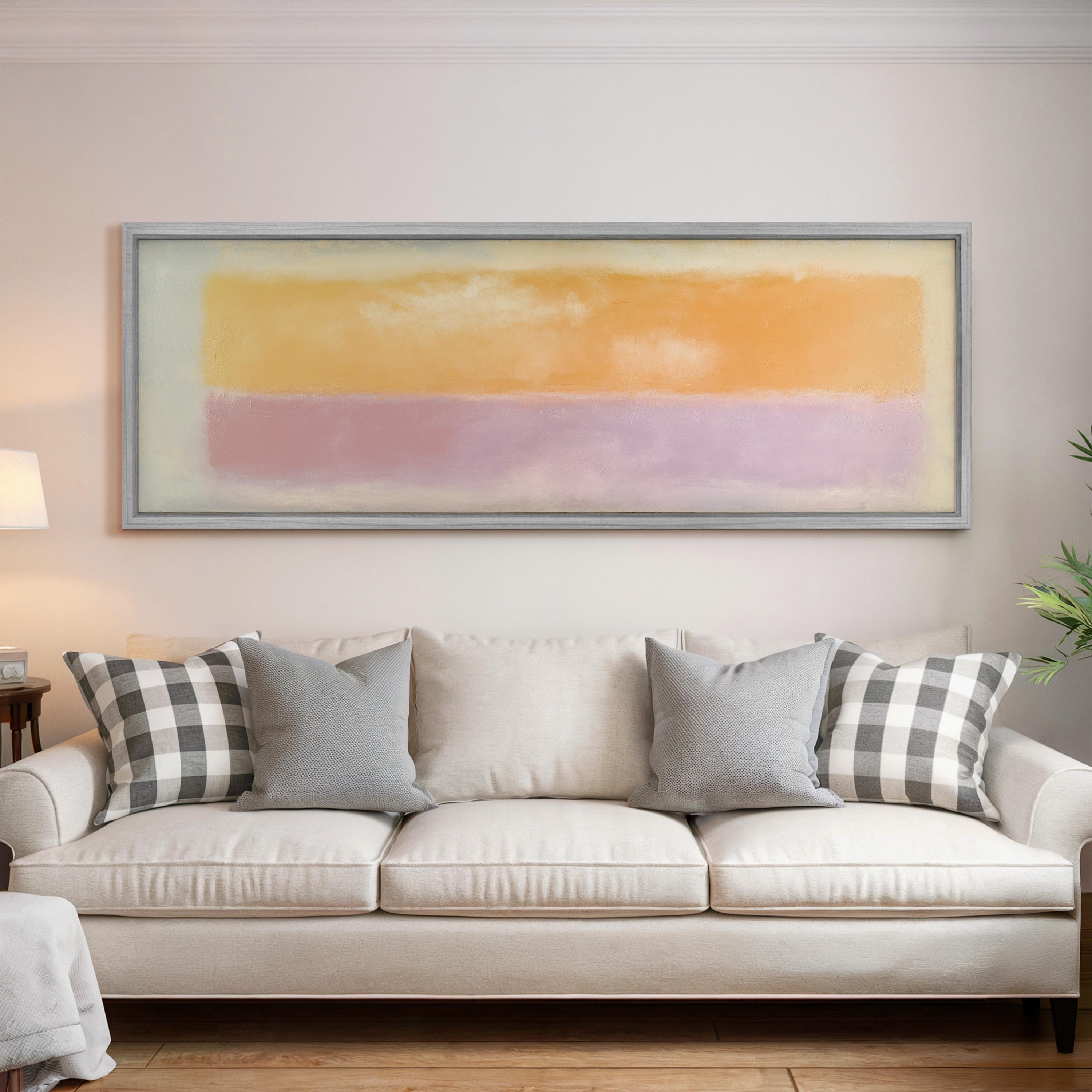 a living room with a white sofa adorned with gray and white plaid throw pillows. Above the sofa, there is a large framed painting depicting a colorful abstract landscape.