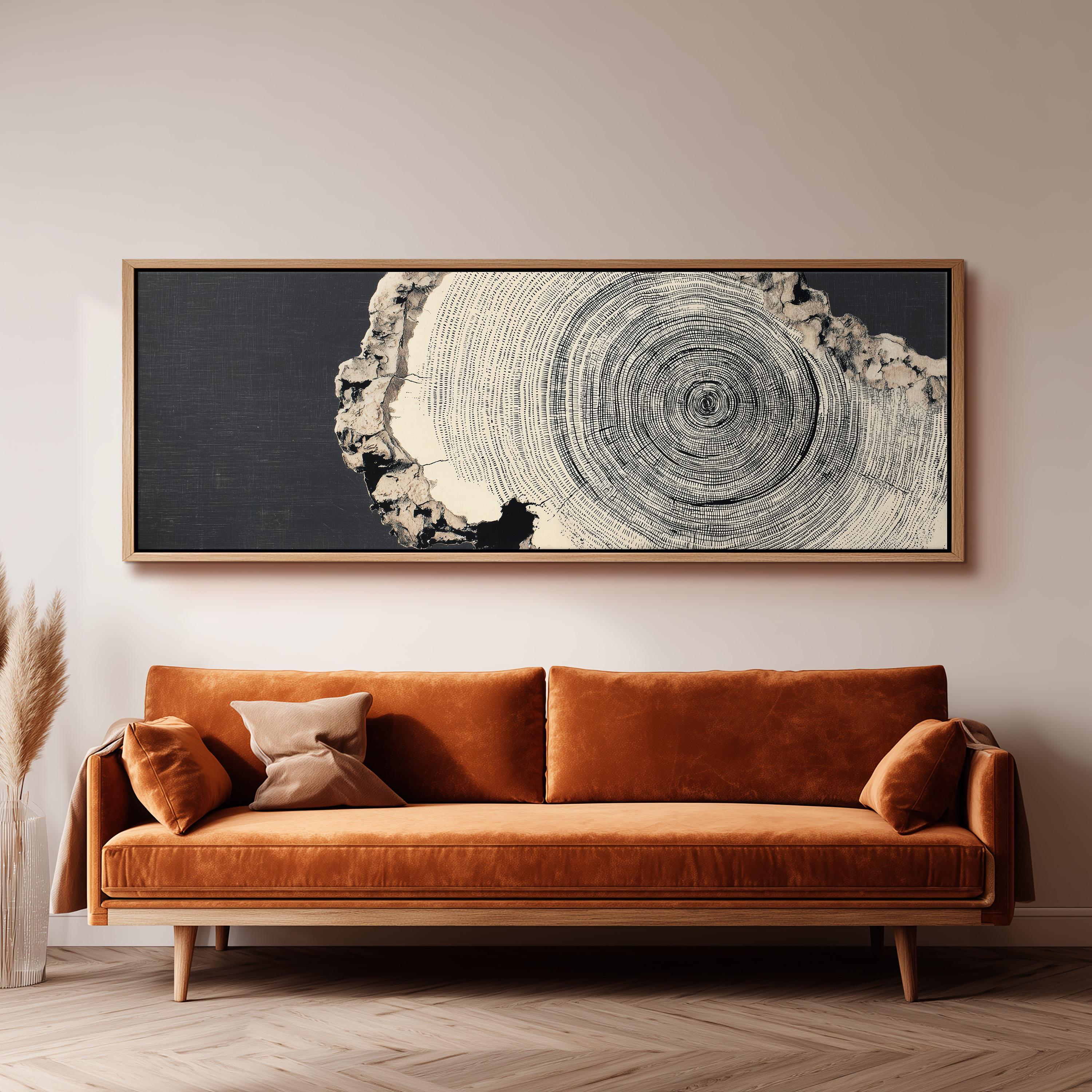 a large black and white tree trunk with concentric circles, hanging above a brown sofa with a wooden frame.