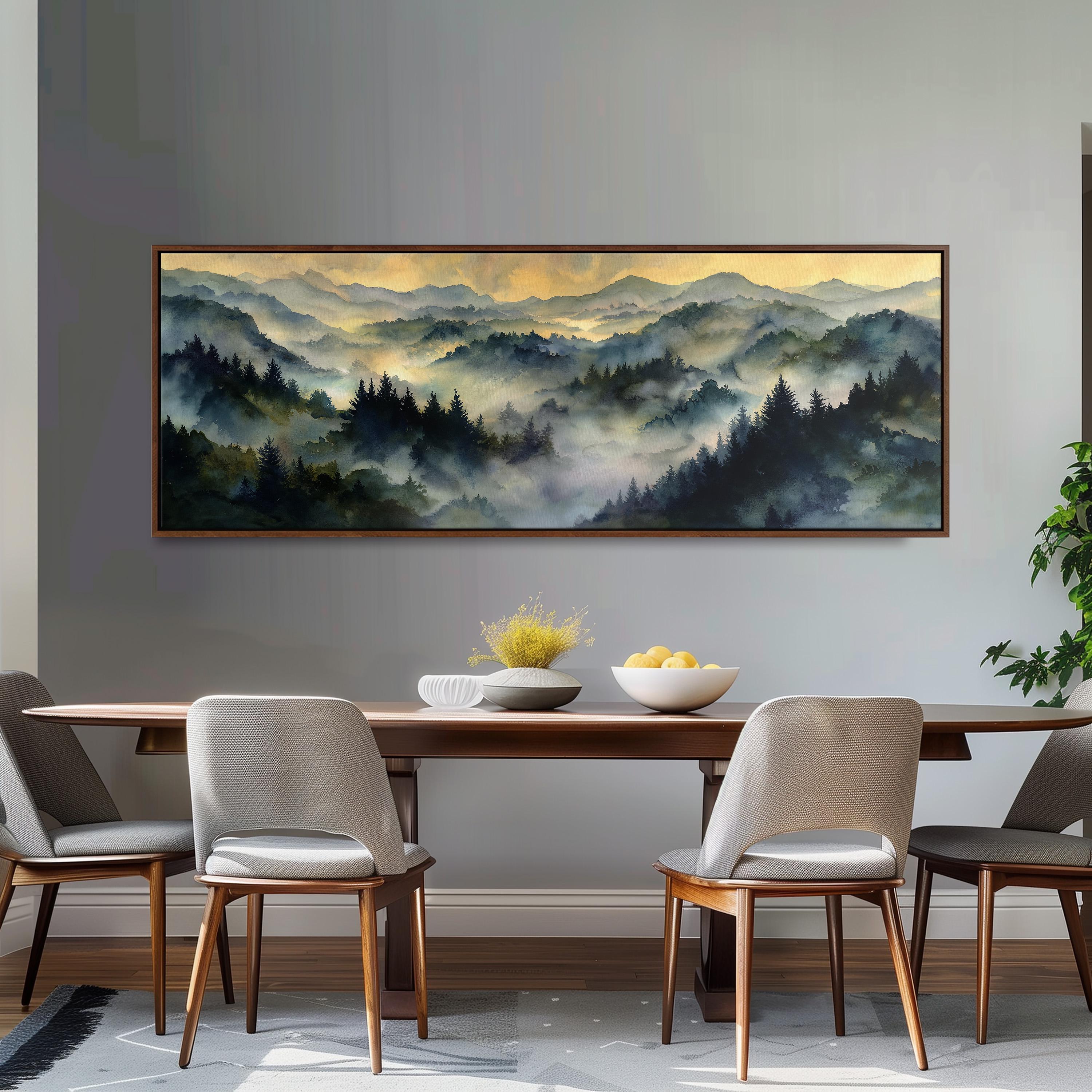a large painting of a mountainous landscape hanging on a wall above a wooden dining table with four chairs. The painting depicts a serene and picturesque scene of a forested mountain range with a hazy, misty atmosphere.