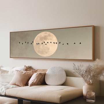 Geese crossing a full moon on grey long horizontal canvas print above a sofa in a living room