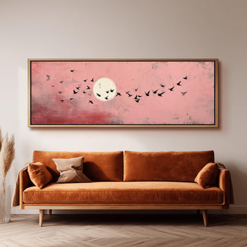 a large, framed painting of a flock of birds flying against a pink sky with a full moon.