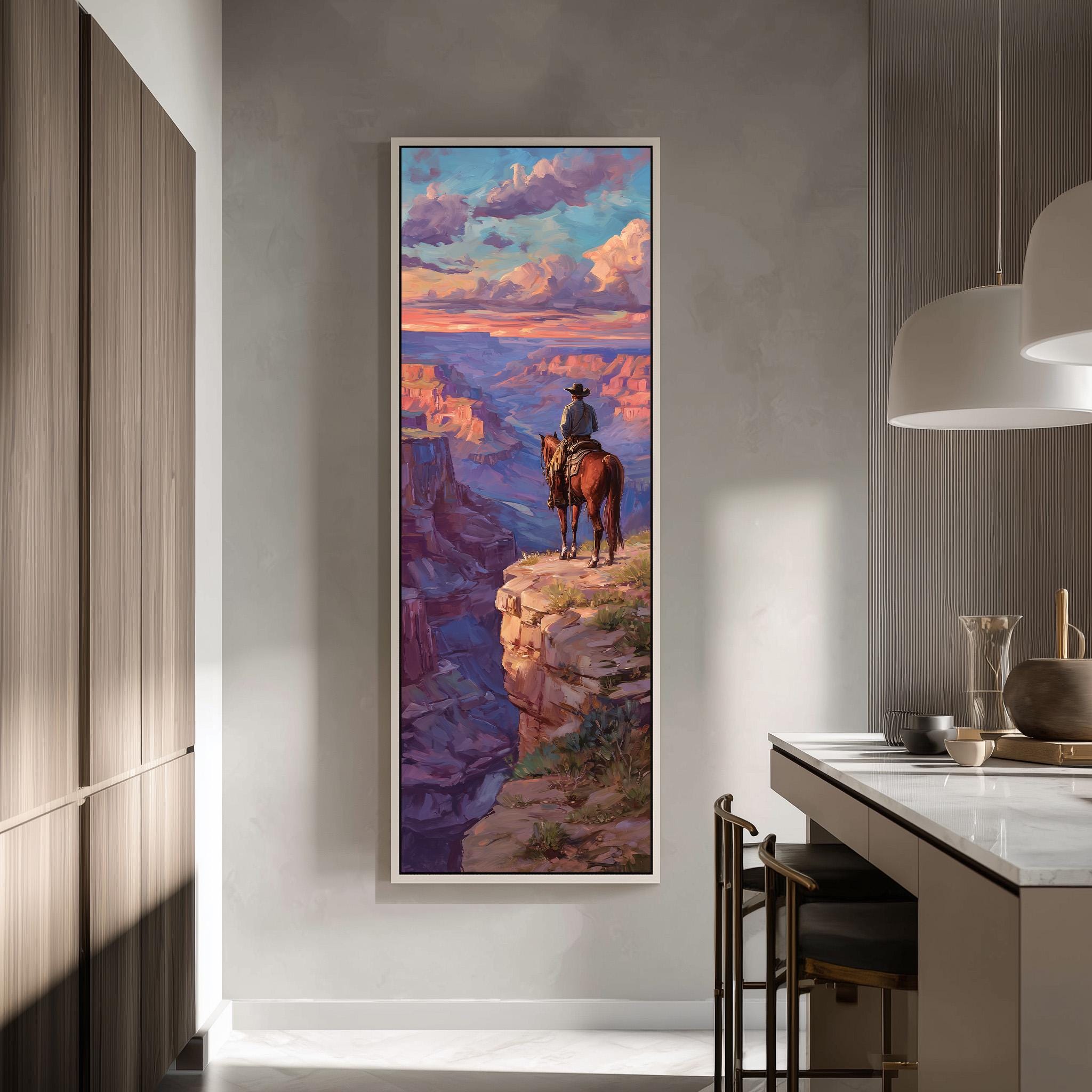 a large framed painting of a cowboy riding a horse on a cliff overlooking a canyon.