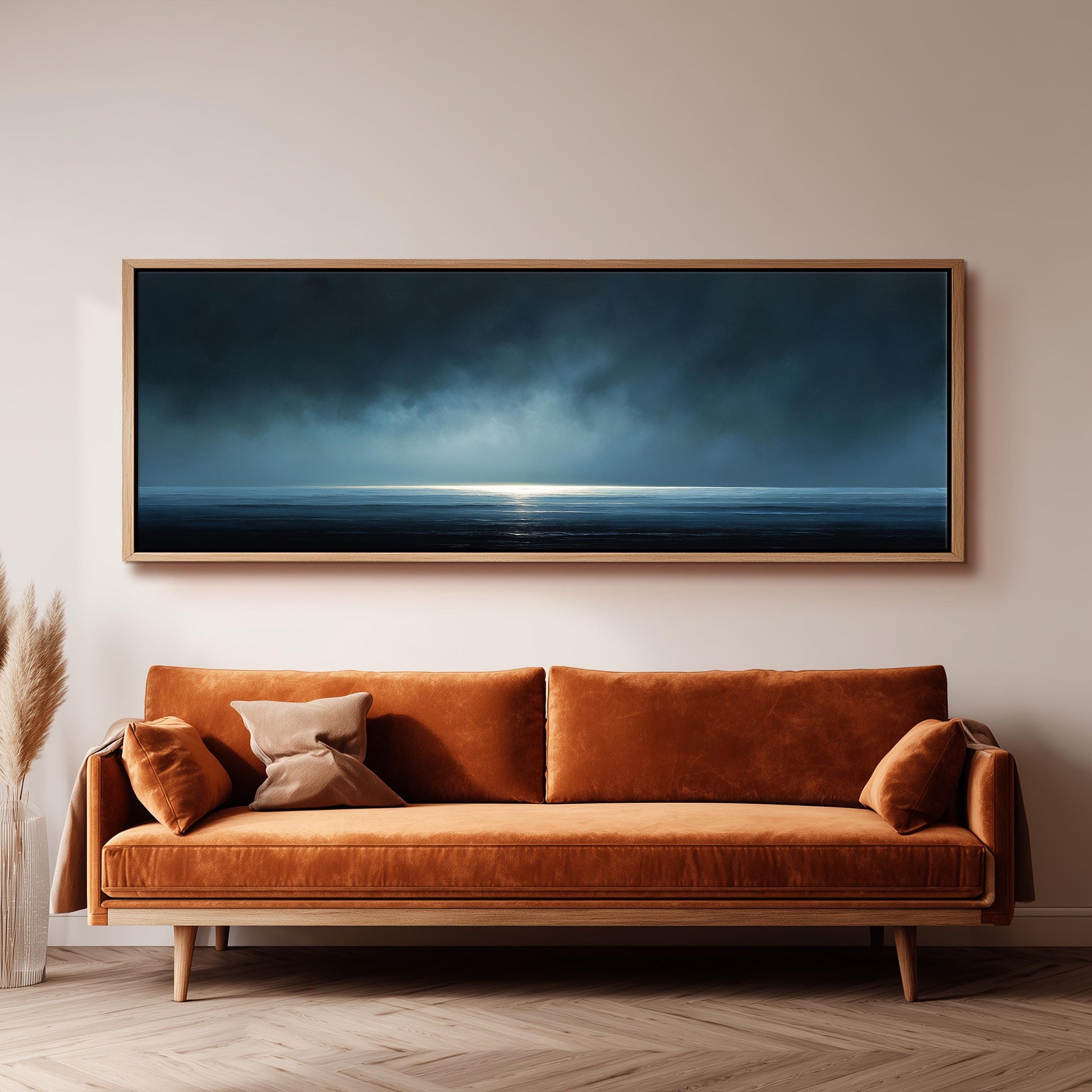 a large, rectangular painting hanging on a wall above a brown sofa with orange cushions.