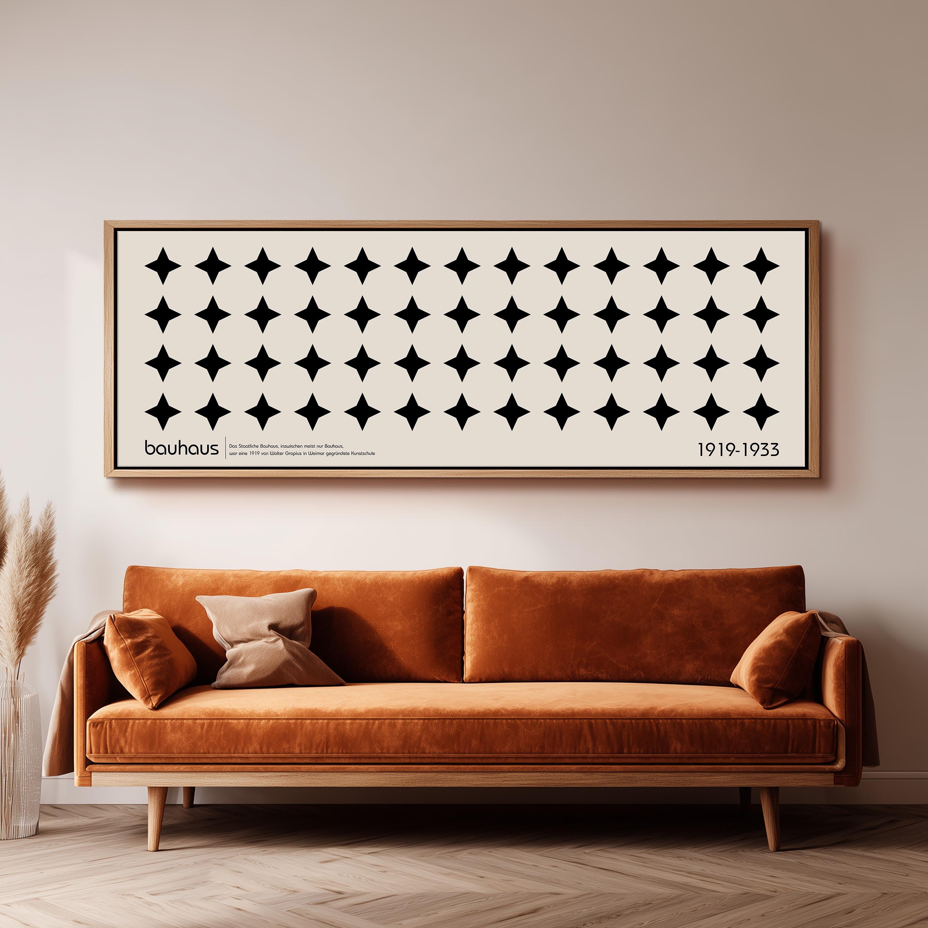 a large black and white abstract art piece with a repeating pattern of black circles and white stars, hanging on a wall above a brown sofa.