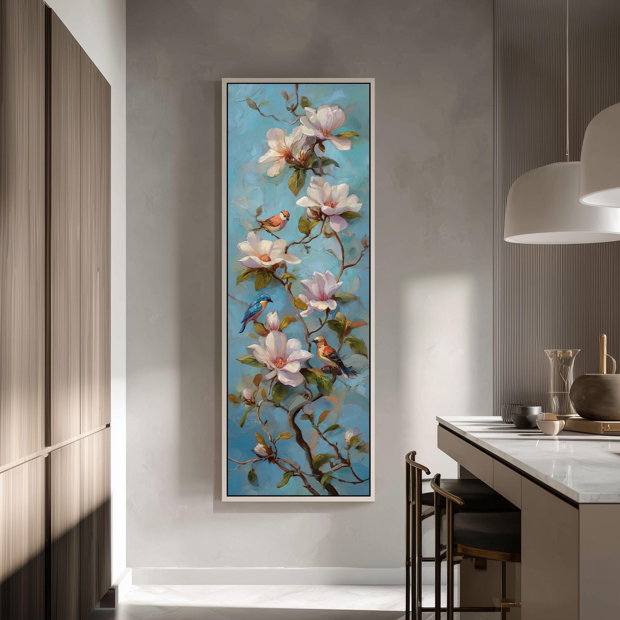 a large painting of a branch with pink and white flowers, along with several birds perched on the branches. The painting is hung on a wall in a room with a kitchen counter and chairs visible in the background.