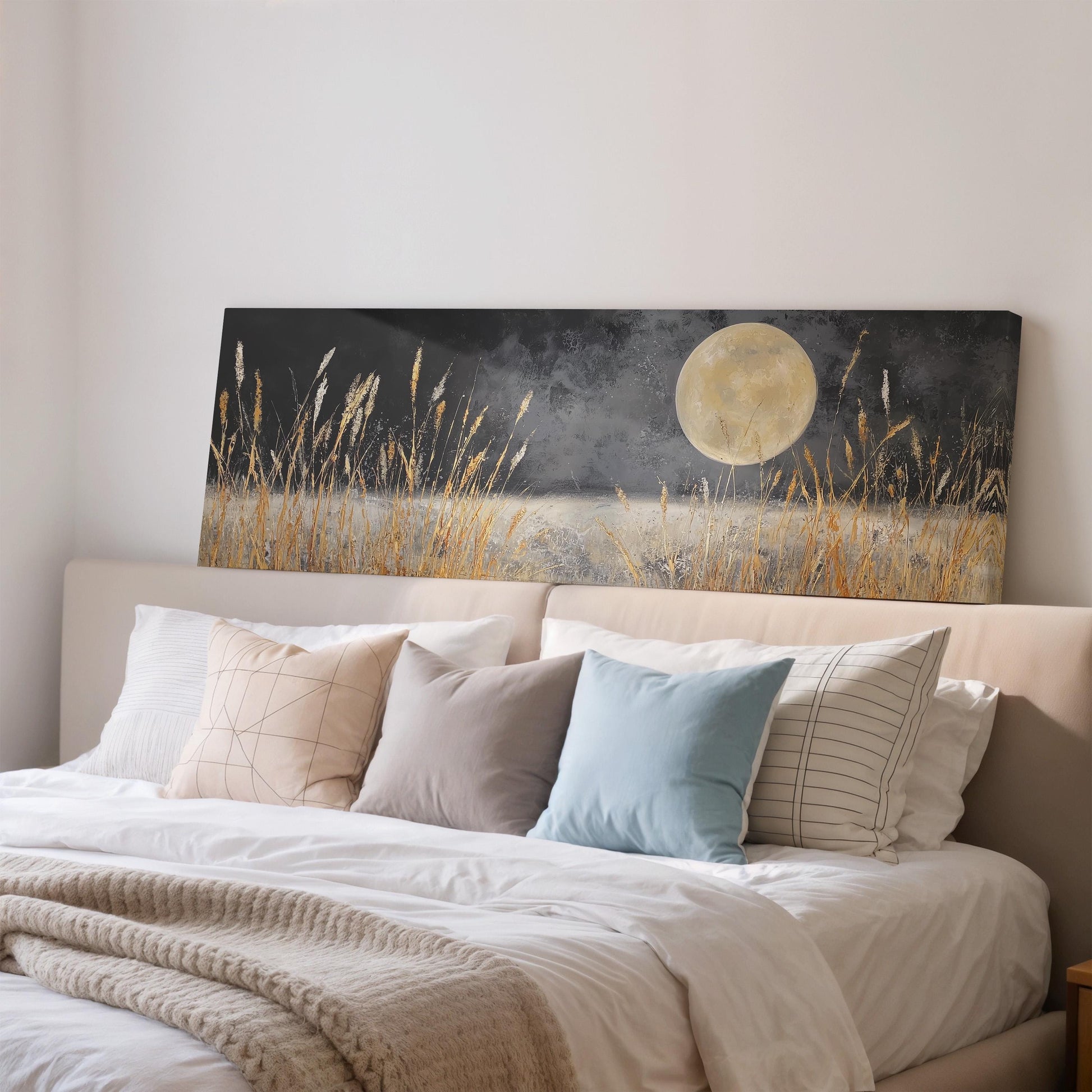 a large bed with a white comforter and pillows, and a painting of a field with tall grass and a full moon on the wall above it.